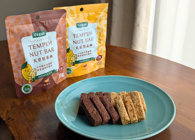 皿に盛り付けられたテンペバー２種類（プレーンとチョコ）。ヴィーガン認証マーク付き。